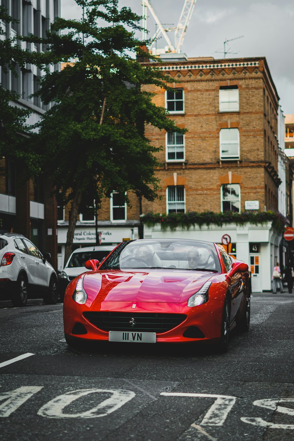 a red sports car driving down a city street