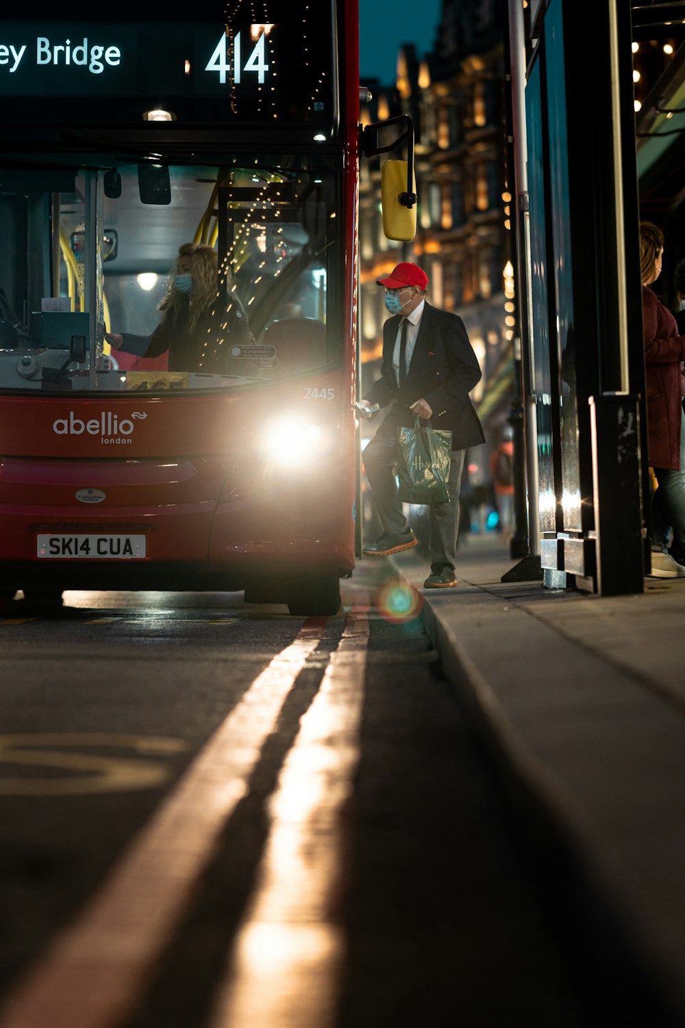 a red bus driving down a street next to a tall building