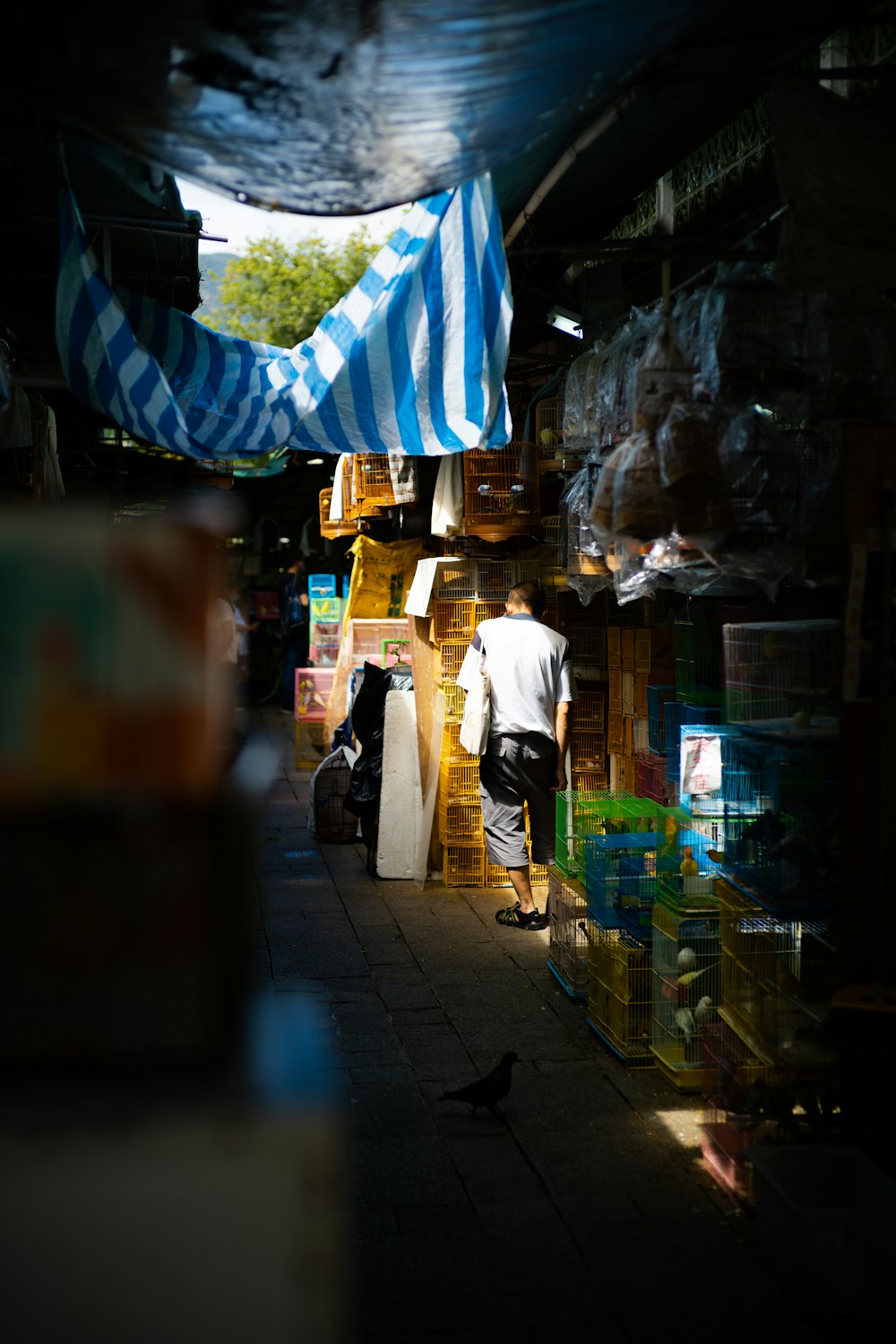 a man is standing in a market with a blue and white striped umbrella