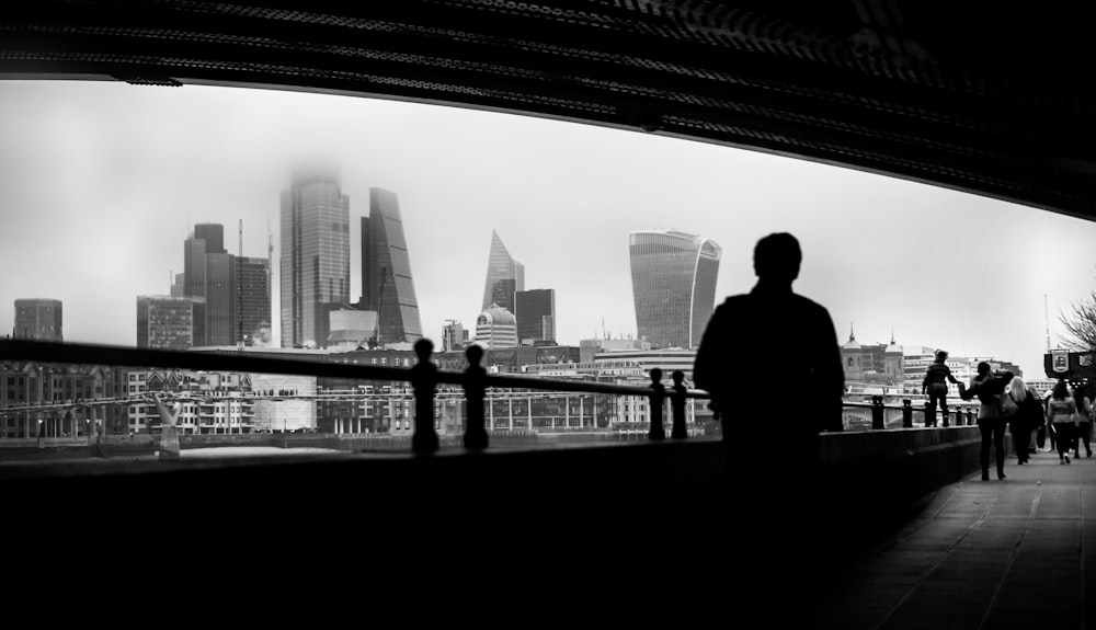 a black and white photo of a man looking at the city