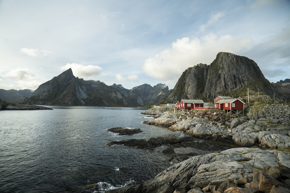 a house on a rocky shore with mountains in the background