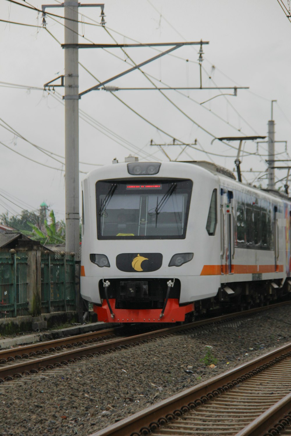 a white train traveling down train tracks next to a building