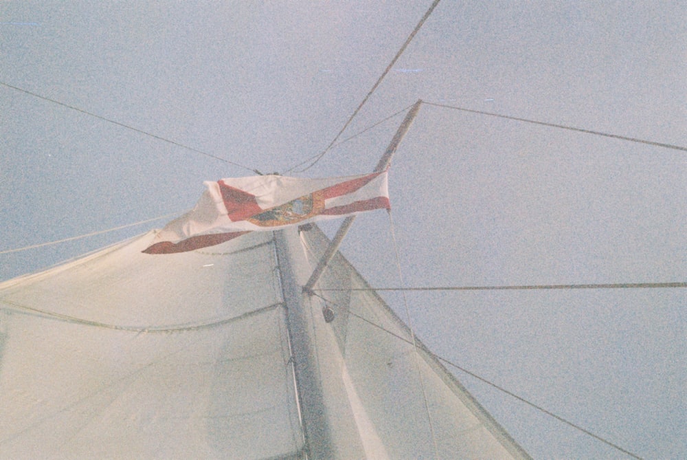 a white sail with a red and white flag on it