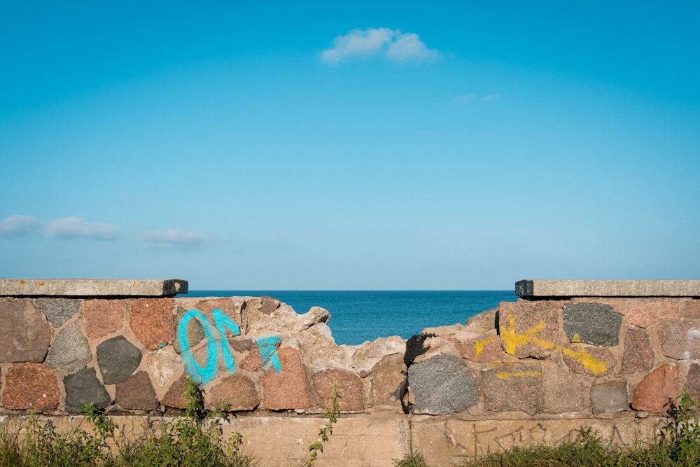 Un muro de piedra con graffiti junto al océano