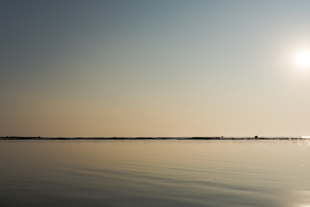 a large body of water with the sun in the background