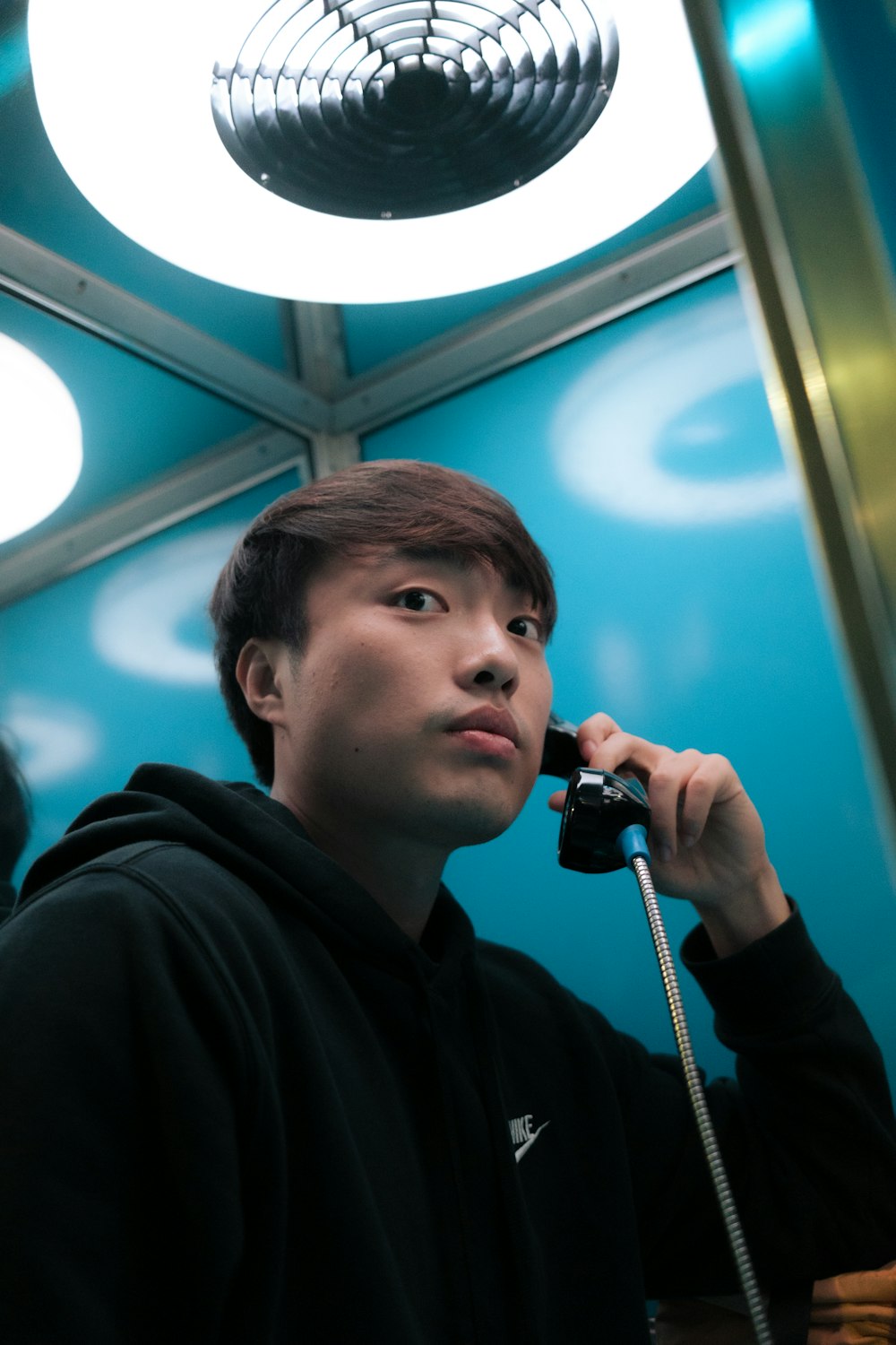 a man in a black hoodie talking on a phone