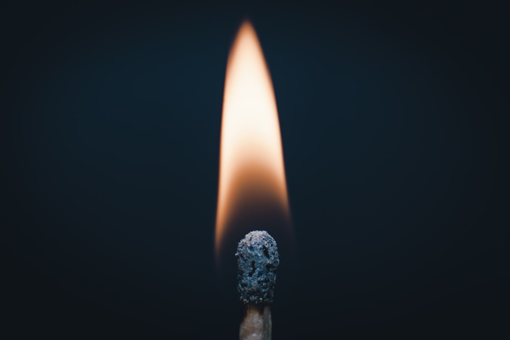 a matchstick with a lit match on a black background