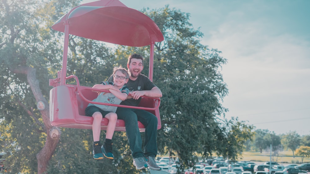 a man and a little girl riding a pink swing ride