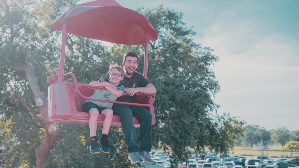 Un hombre y una niña montando un columpio rosa