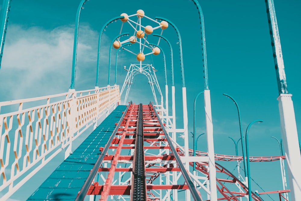 a red and white roller coaster against a blue sky