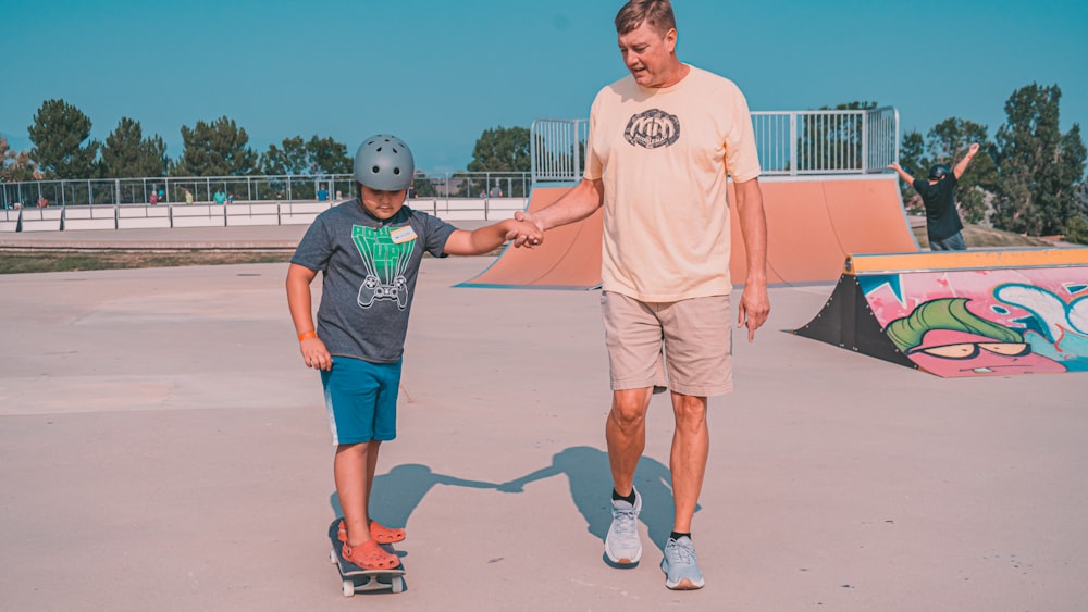 a man holding the hand of a boy on a skateboard