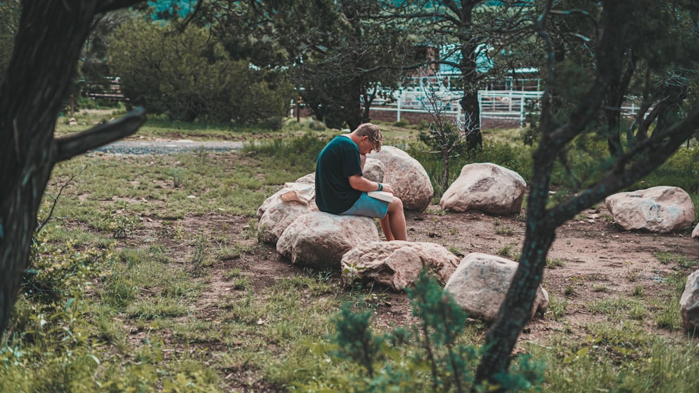 a man sitting on a rock in the middle of a field