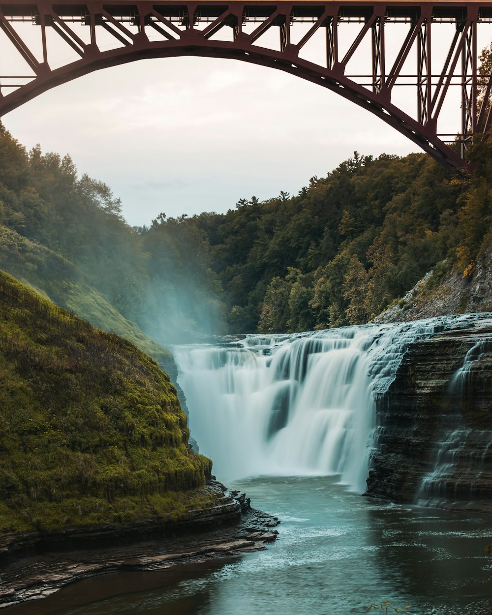 a bridge over a body of water near a waterfall