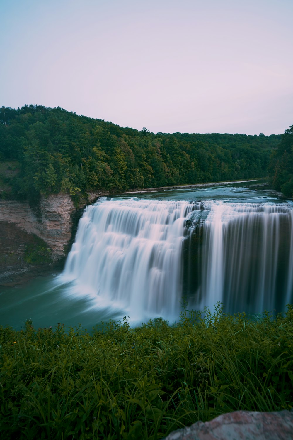 uma grande cachoeira com água em cascata sobre ela