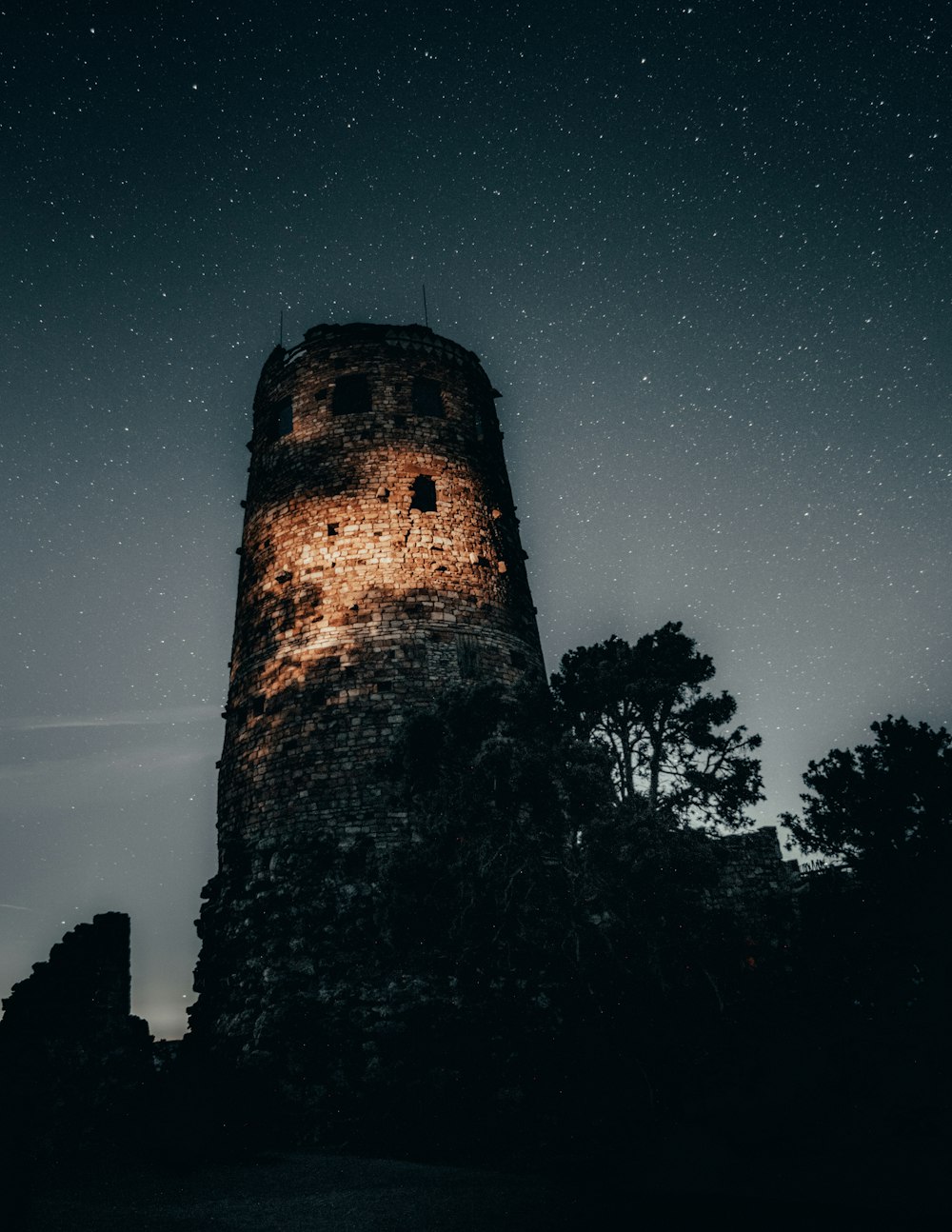 a tall tower with a sky full of stars in the background