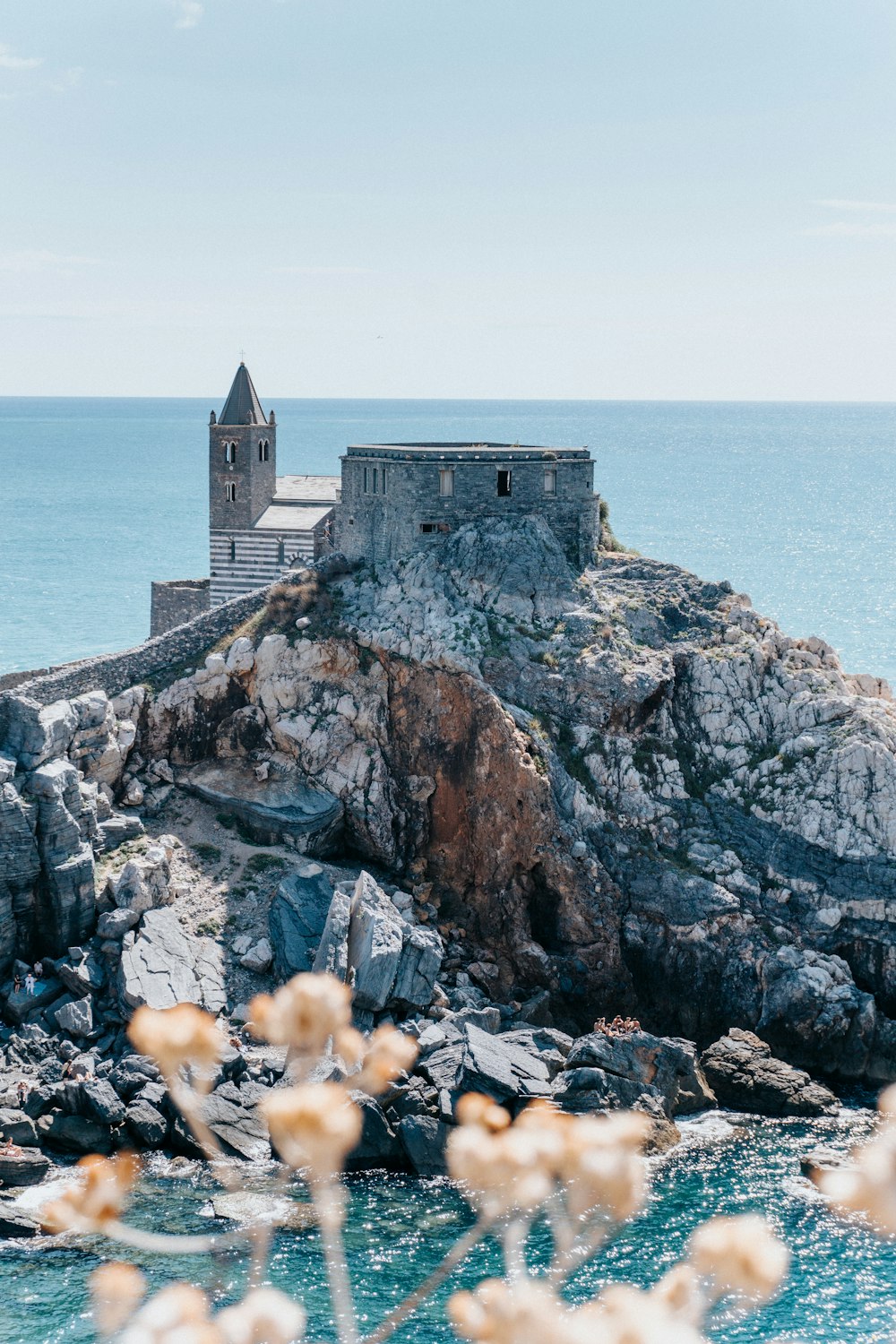 a small building sitting on top of a rocky cliff next to the ocean