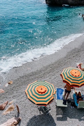 a couple of people sitting under umbrellas on a beach