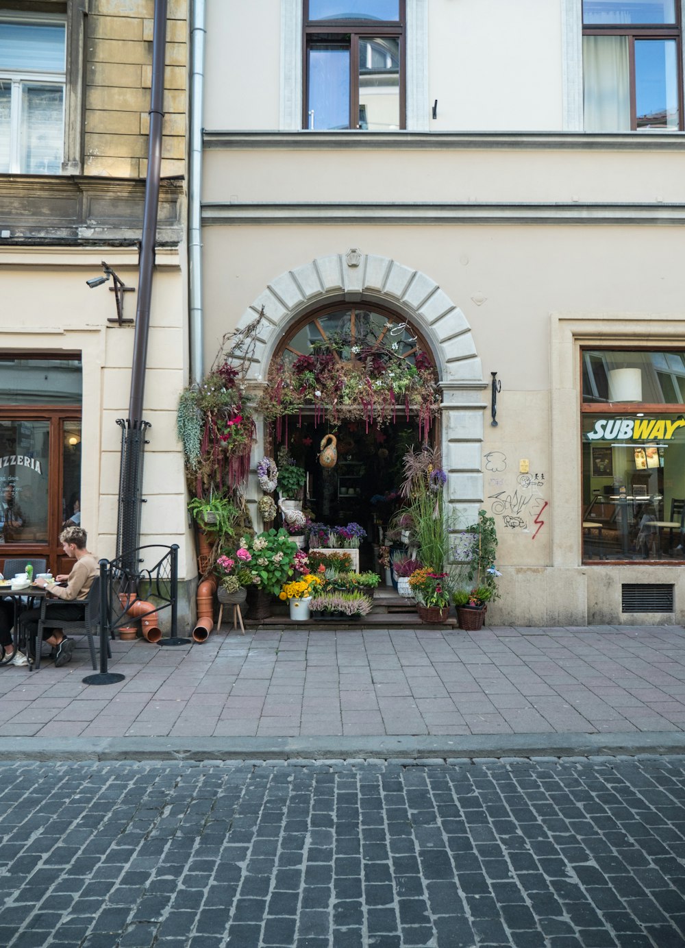 a woman sitting at a table in front of a flower shop