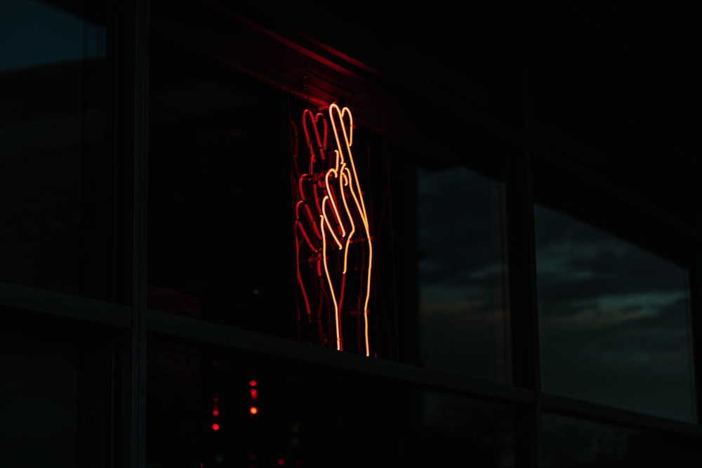 Un letrero de neón rojo frente a una ventana