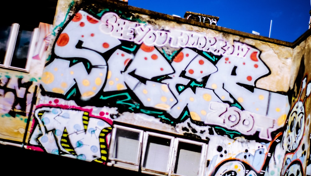 a building covered in lots of graffiti under a blue sky