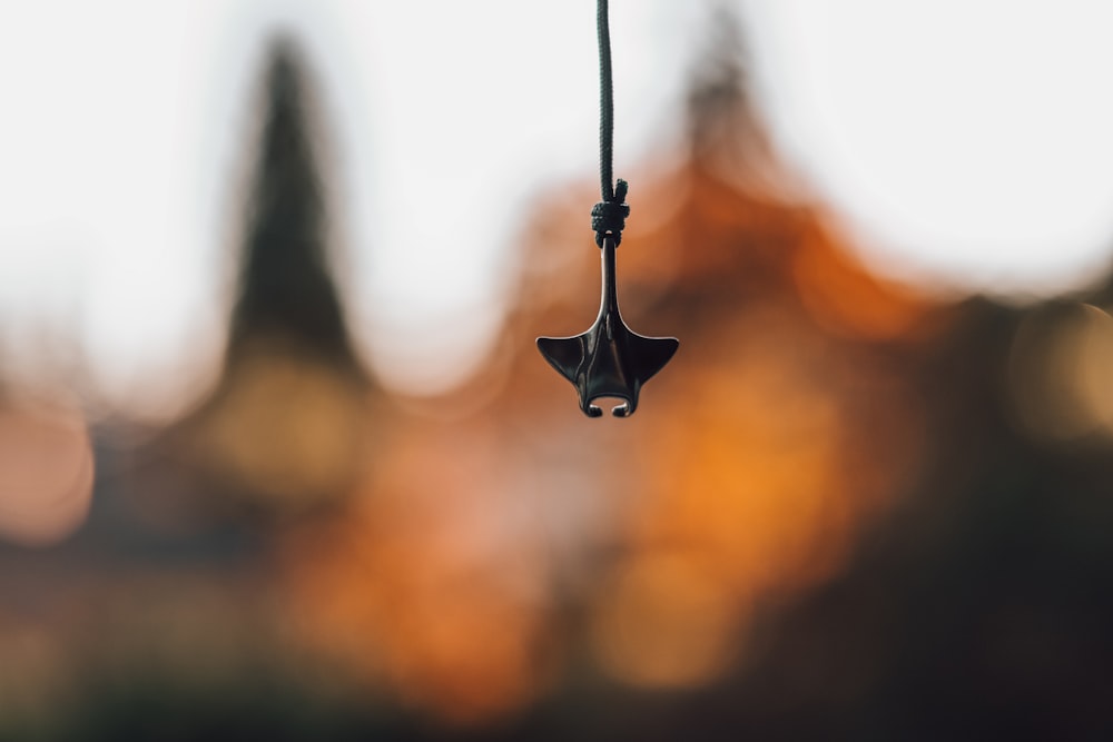a close up of a wind chime with trees in the background