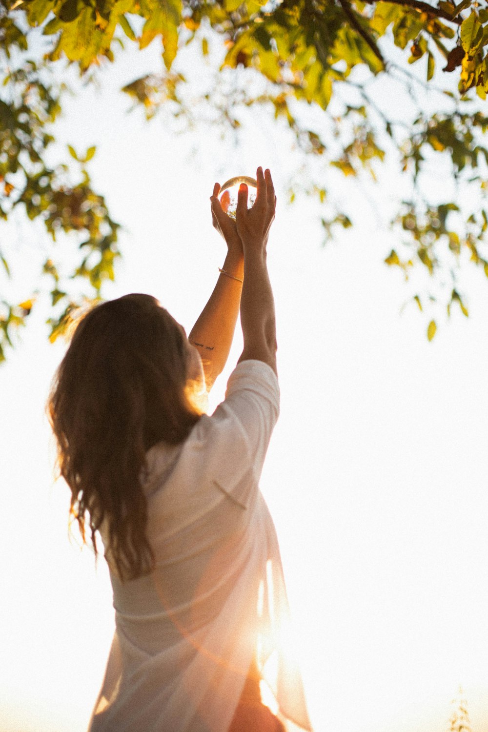 a woman reaching up into the air to catch a frisbee