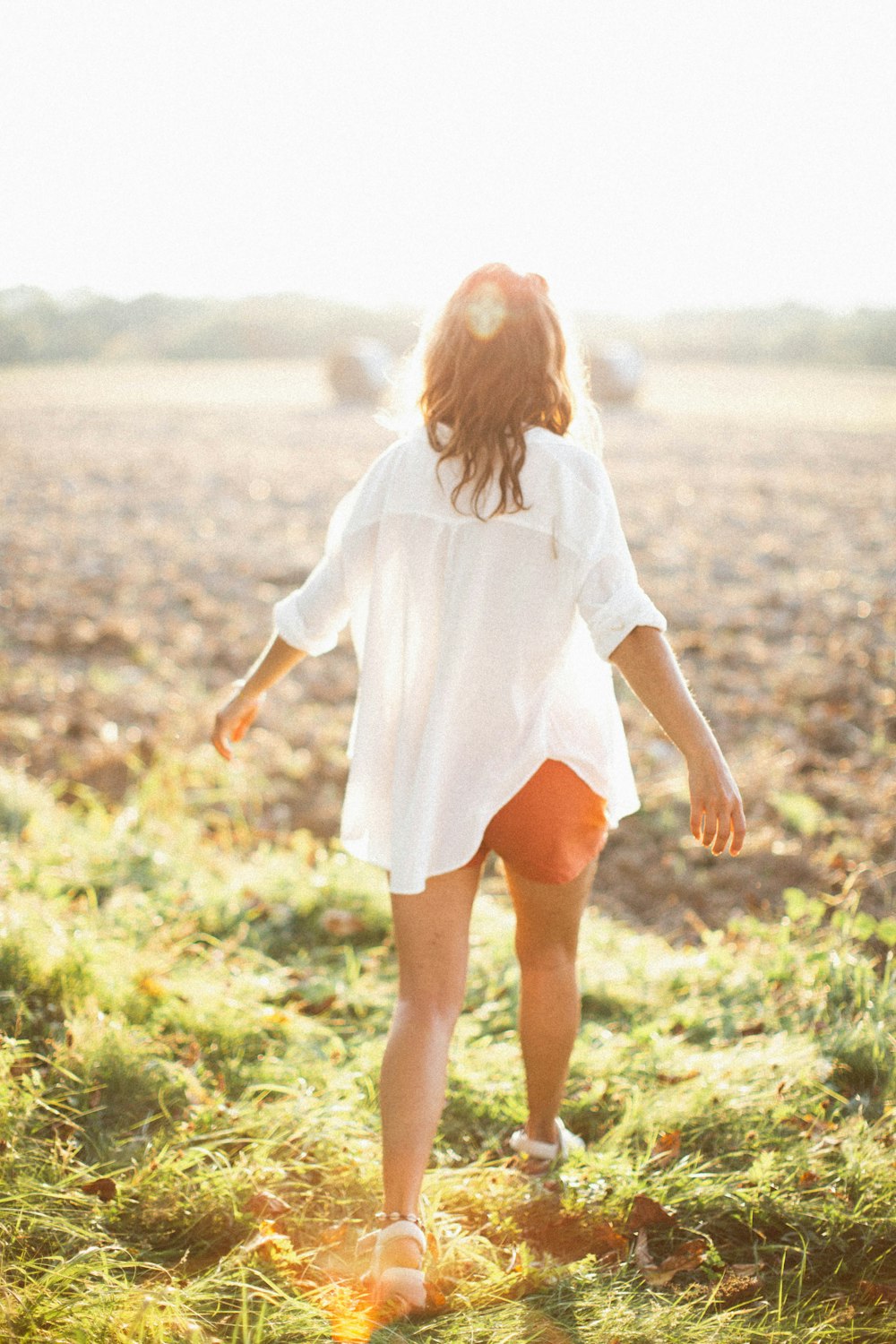 a woman walking through a field of grass