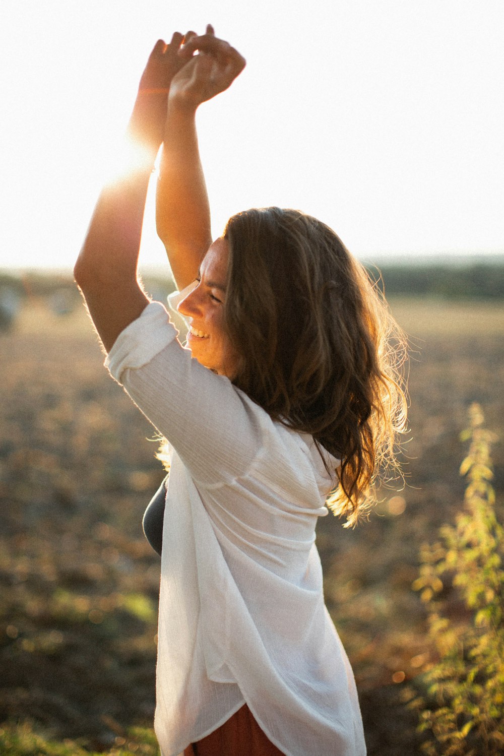 a woman standing in a field holding her arms up