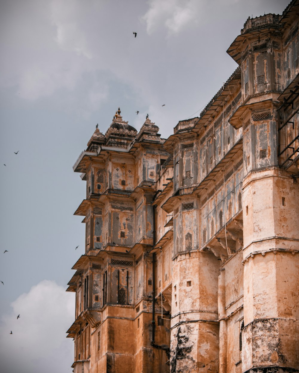 an old building with many windows and birds flying in the sky