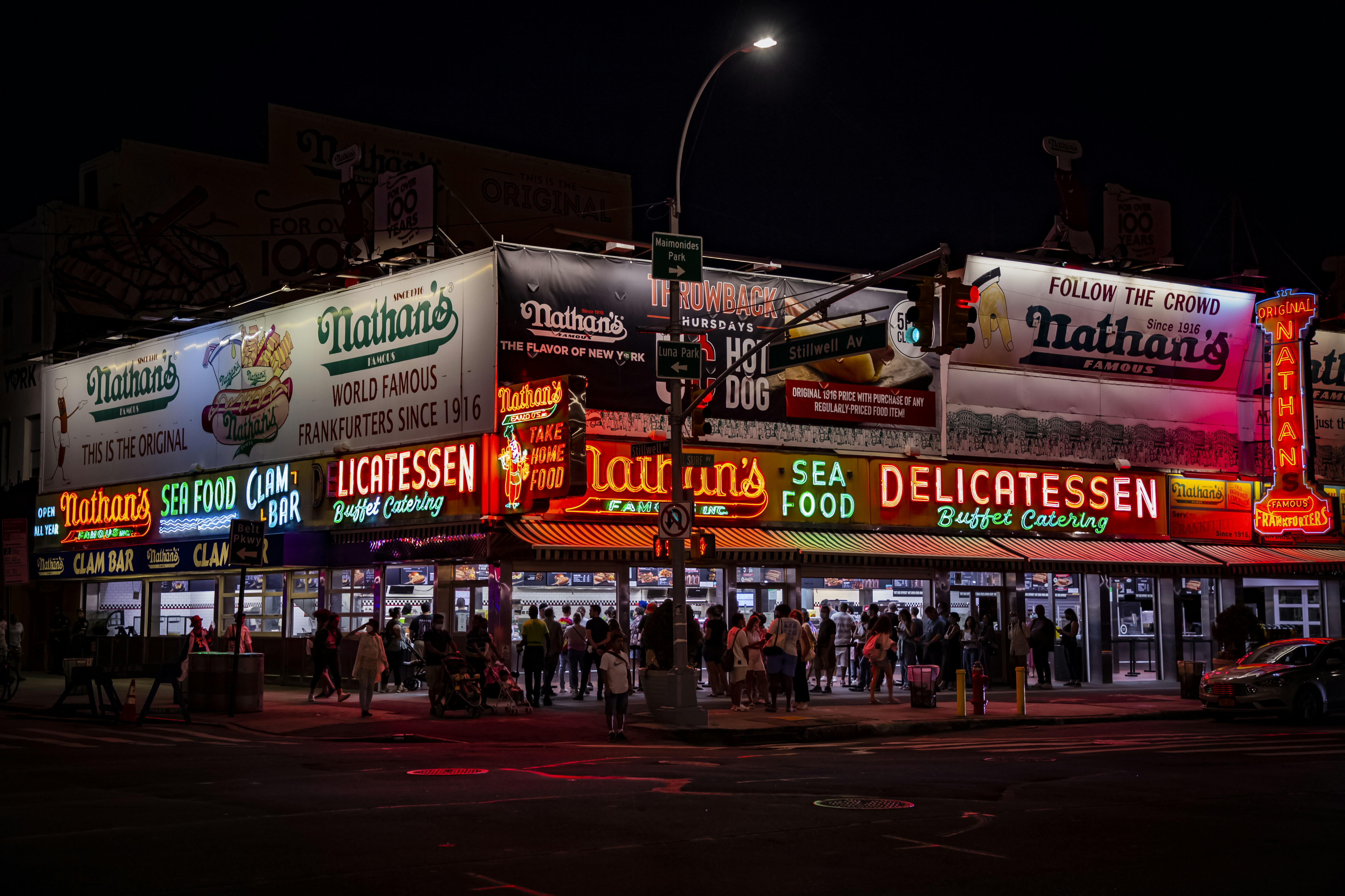 a group of people standing outside of a restaurant at night