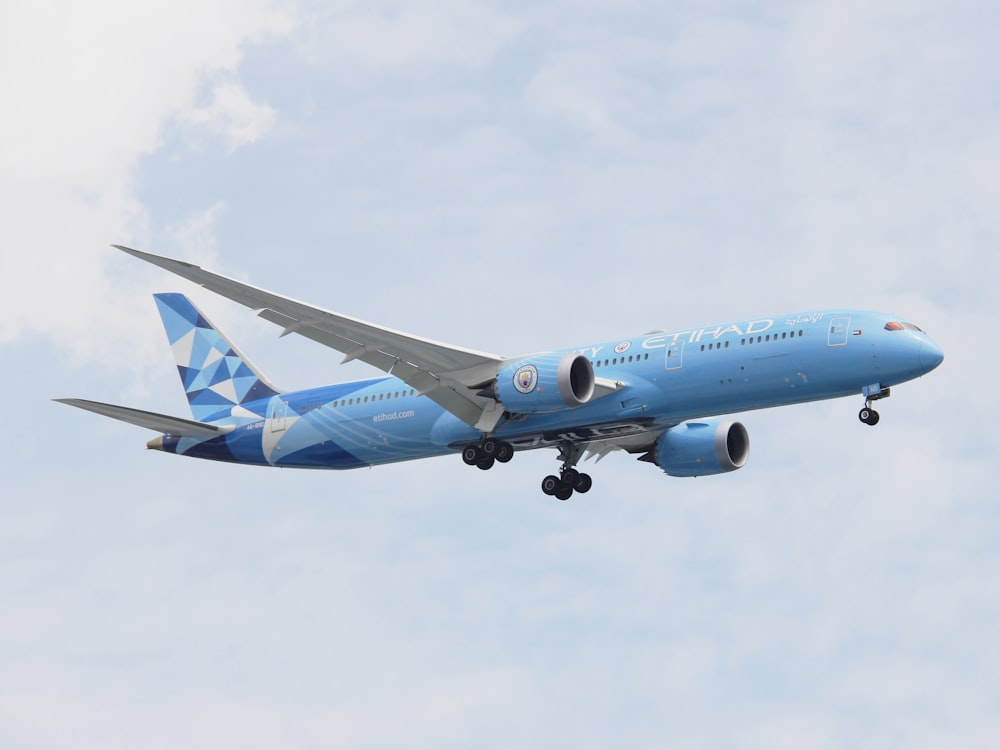 a blue and white airplane flying in the sky