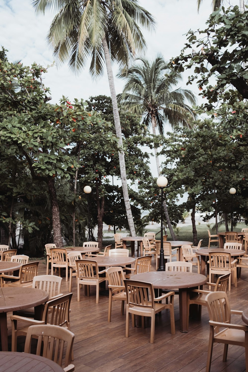 a wooden deck with tables and chairs and a palm tree