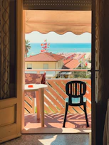 Chic apartment balcony with ocean horizon and comfortable seating.