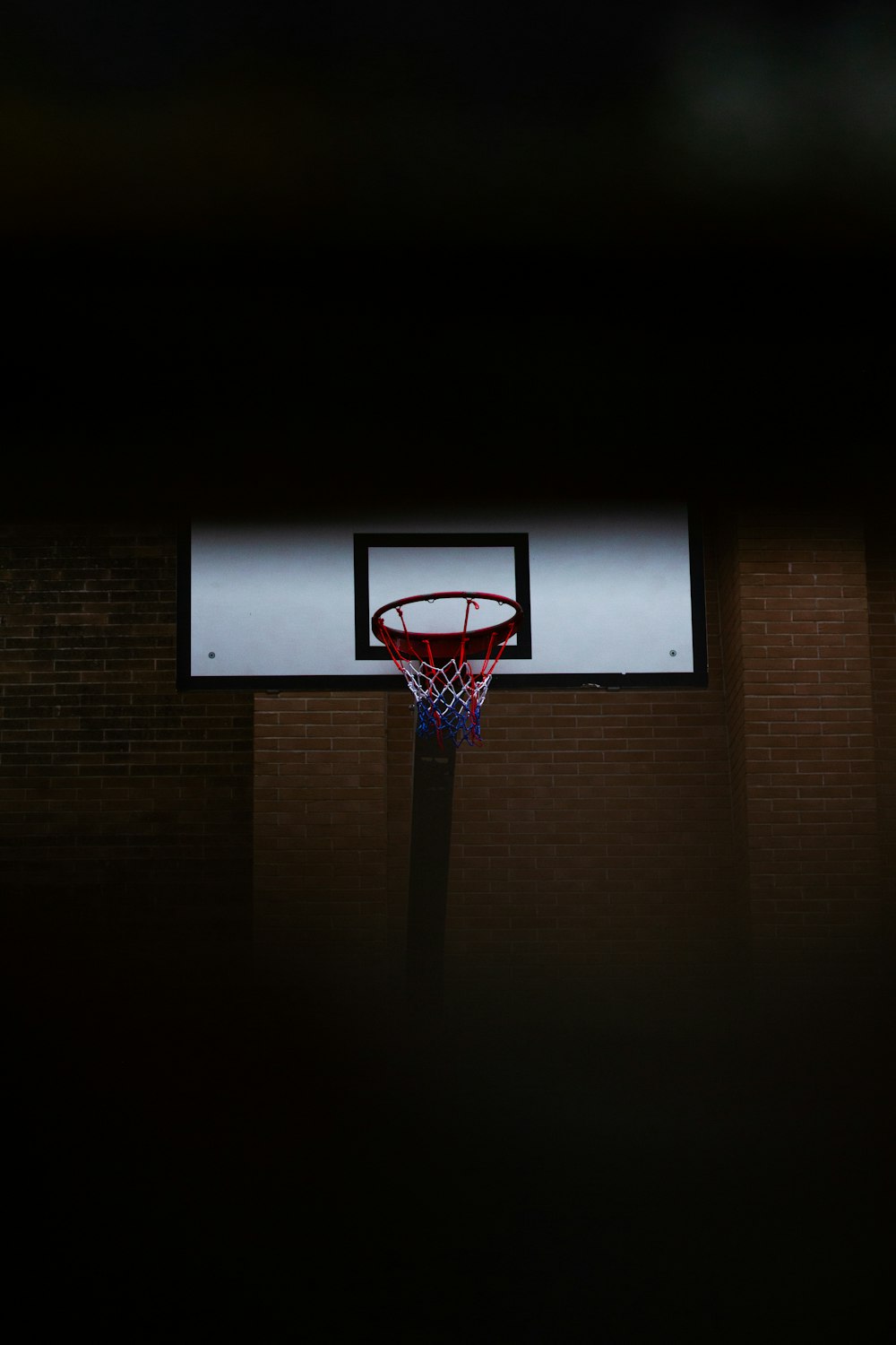 a basketball hoop in a dark room with a brick wall