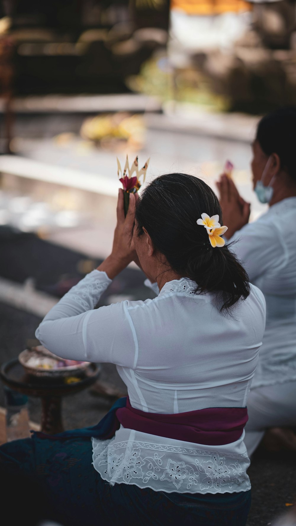 a woman sitting on the ground with a flower in her hair