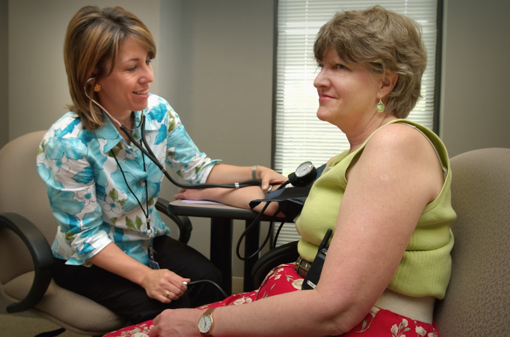 a woman with a stethoscope sitting next to a woman in a chair