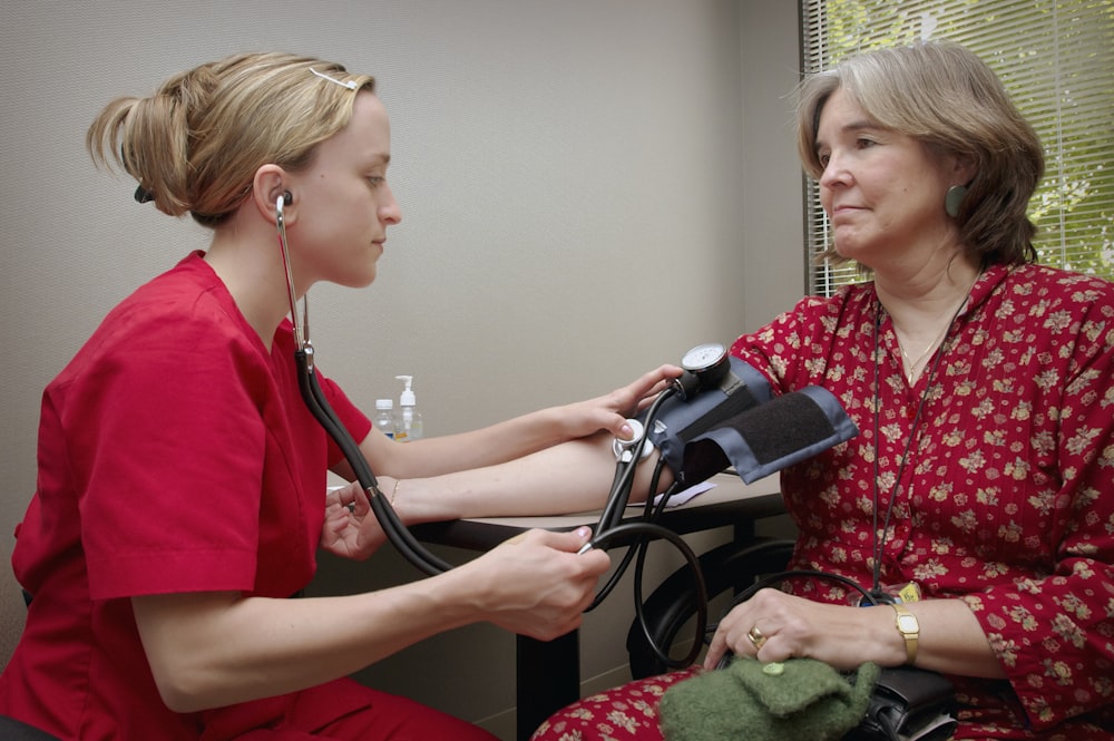 uma mulher com um estetoscópio ouvindo um paciente