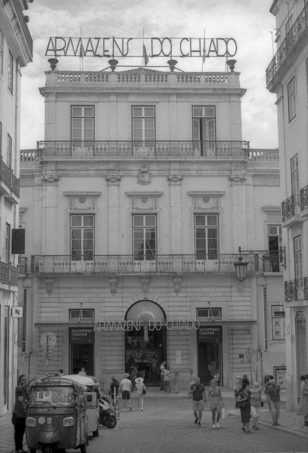 a black and white photo of people walking in front of a building