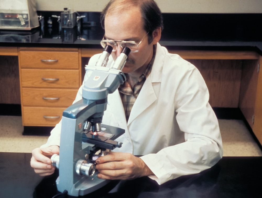 a man in a lab coat looking through a microscope