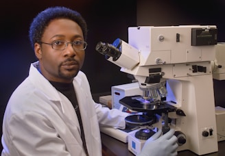 a man in a lab coat is looking into a microscope