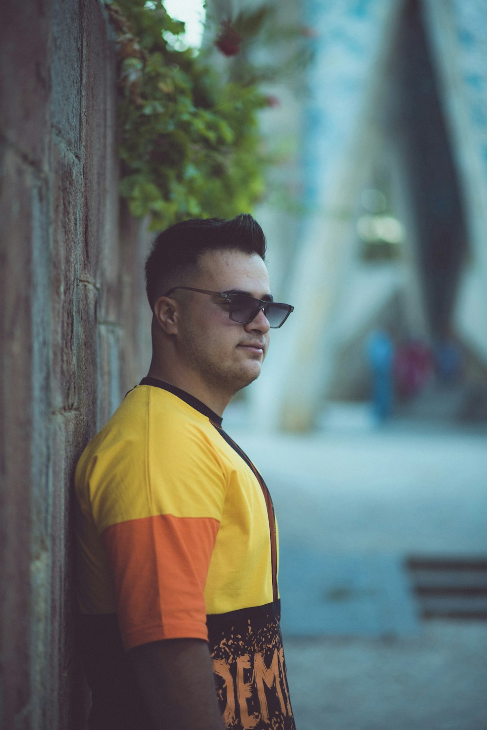 a man wearing sunglasses leaning against a wall