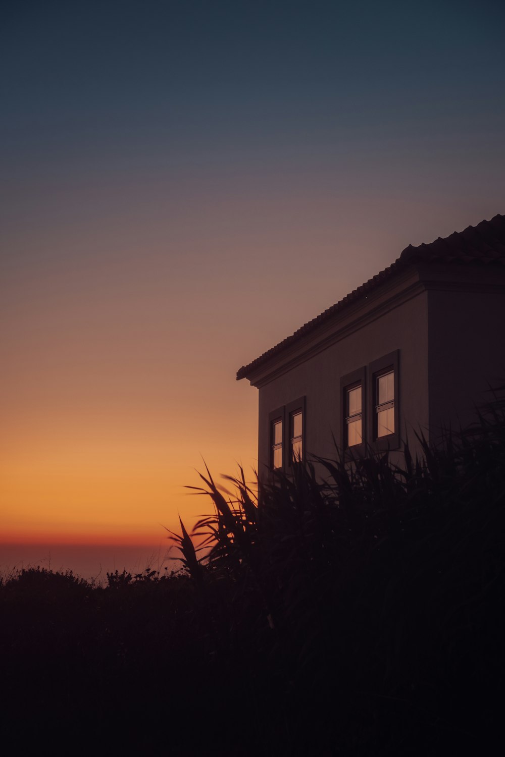 a silhouette of a house against a sunset