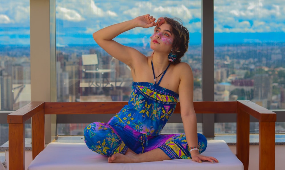 a woman sitting on top of a bed next to a window