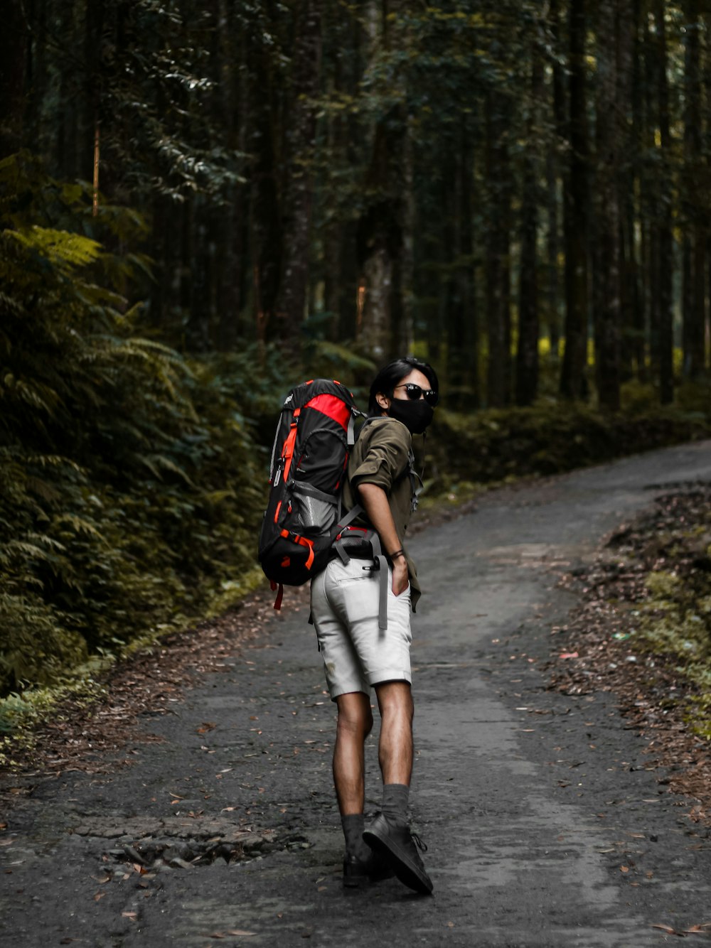 a man with a backpack walks down a path in the woods