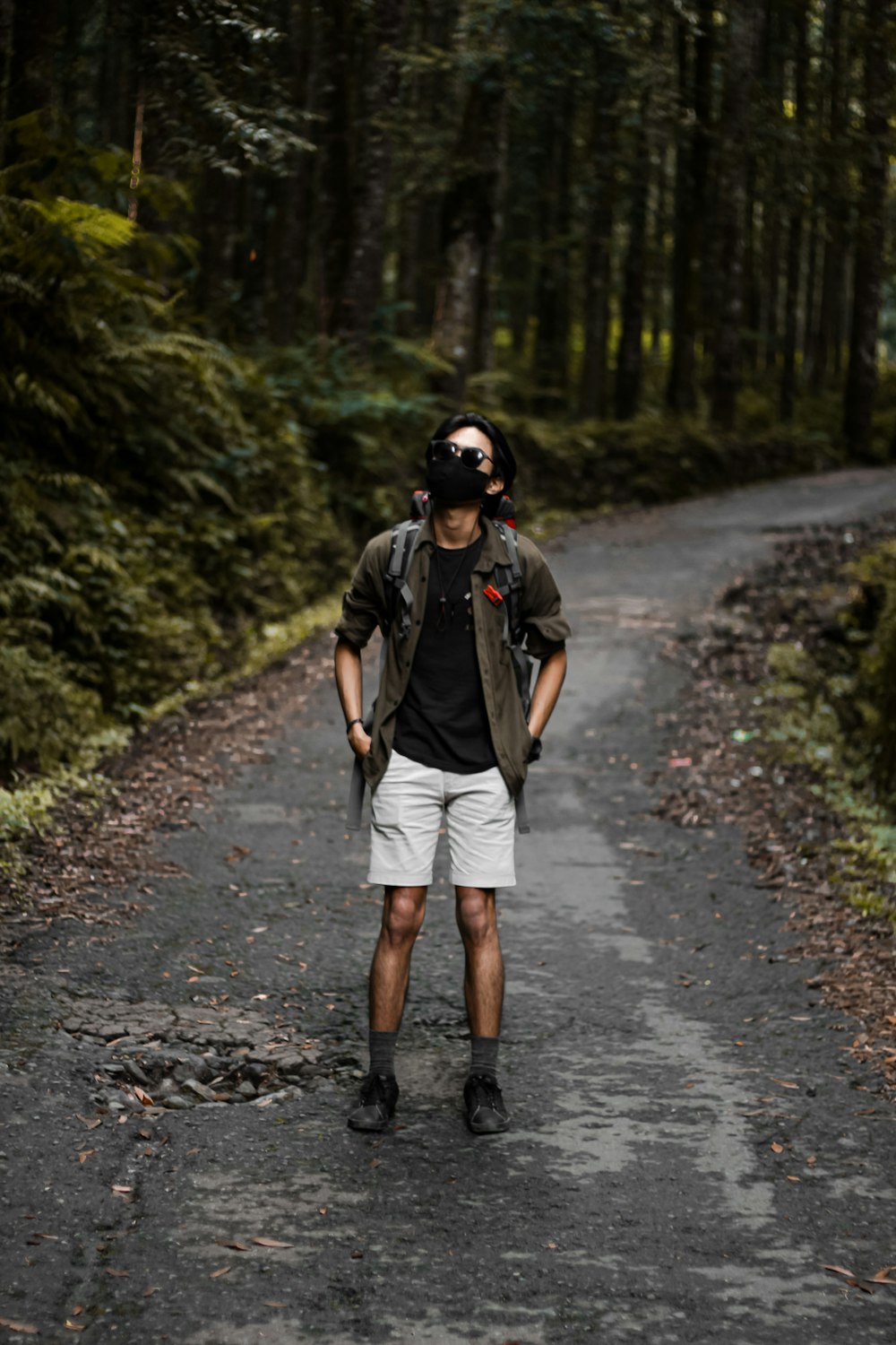 a man standing on a road in the middle of a forest