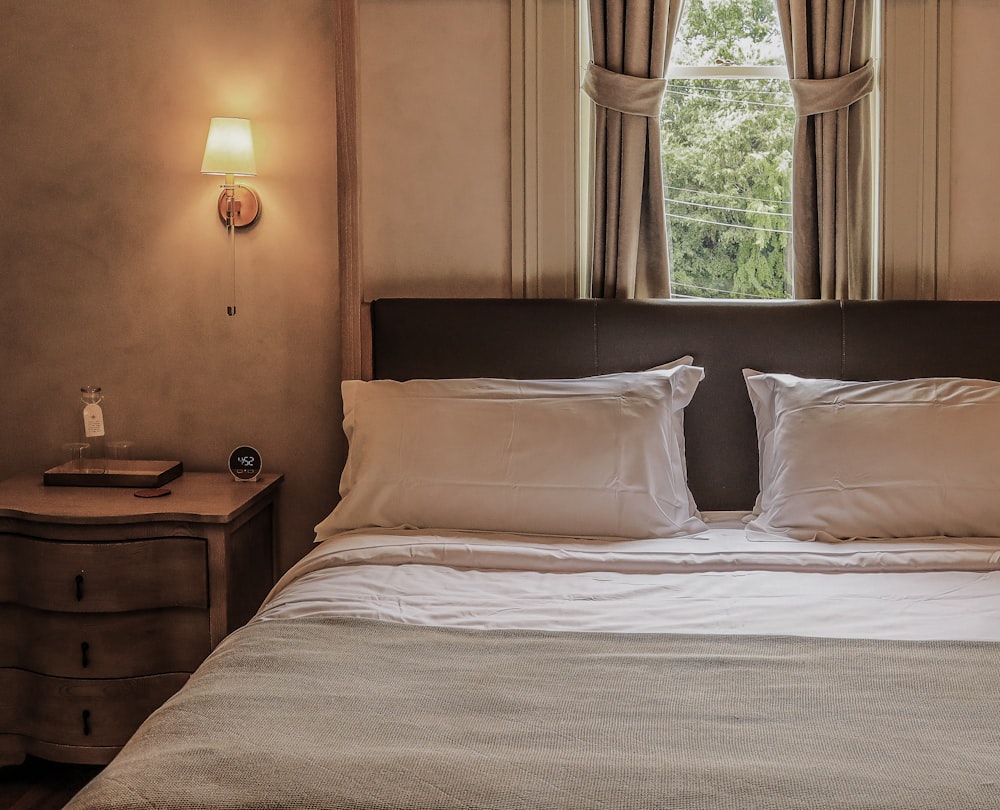 a bed with white sheets and pillows in a bedroom