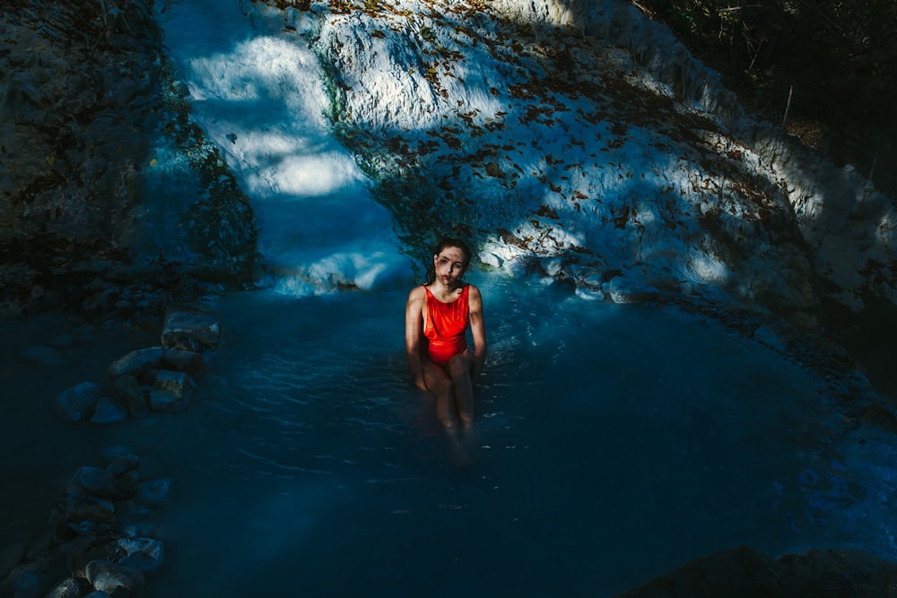 a woman in a red swimsuit standing in a pool of water