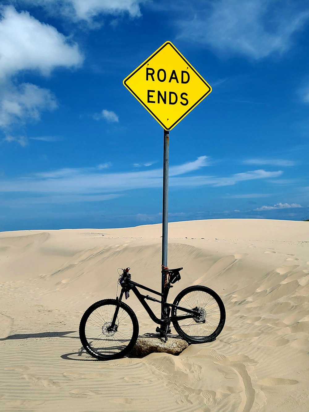 a bike leaning against a road sign in the sand