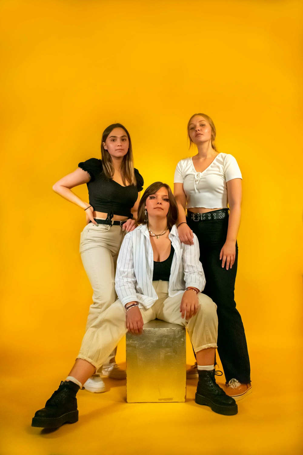 three women posing for a picture in front of a yellow background