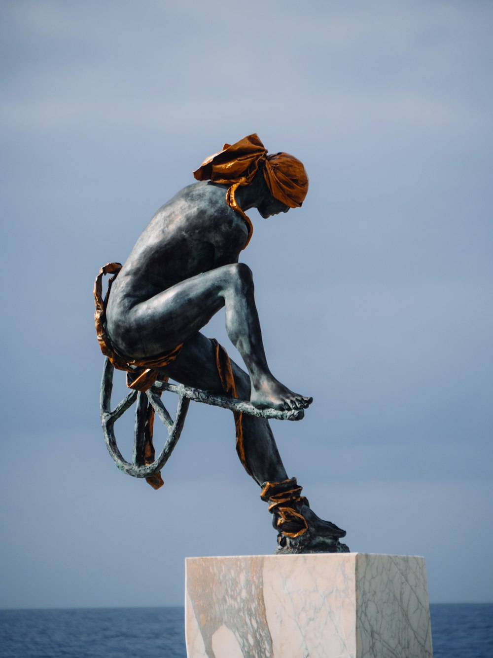 a statue of a person sitting on a wheel chair